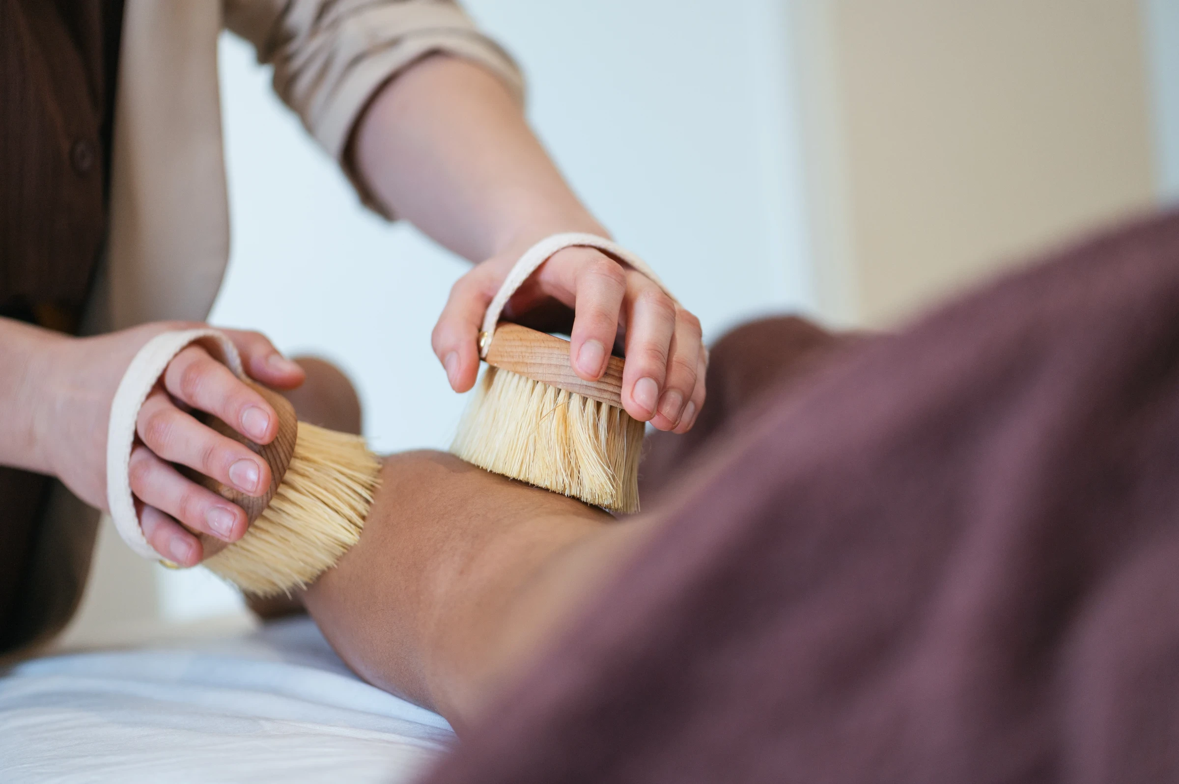 Dry brushing treatment using natural-bristle brushes on the client's arm