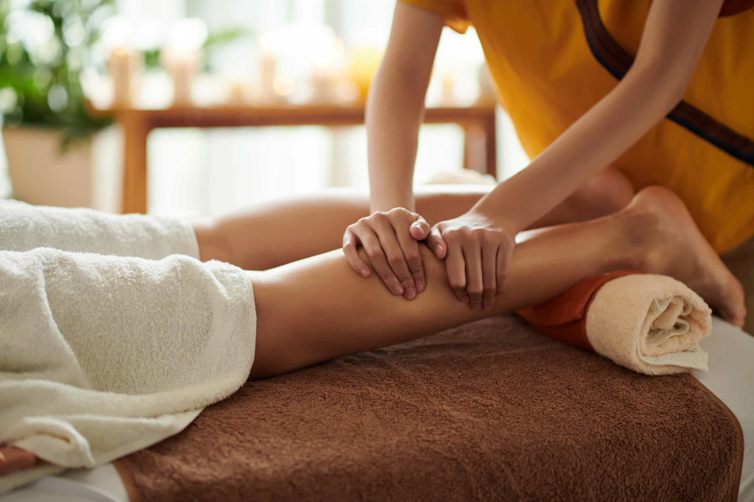Therapist massaging a client's calf muscle on a treatment table