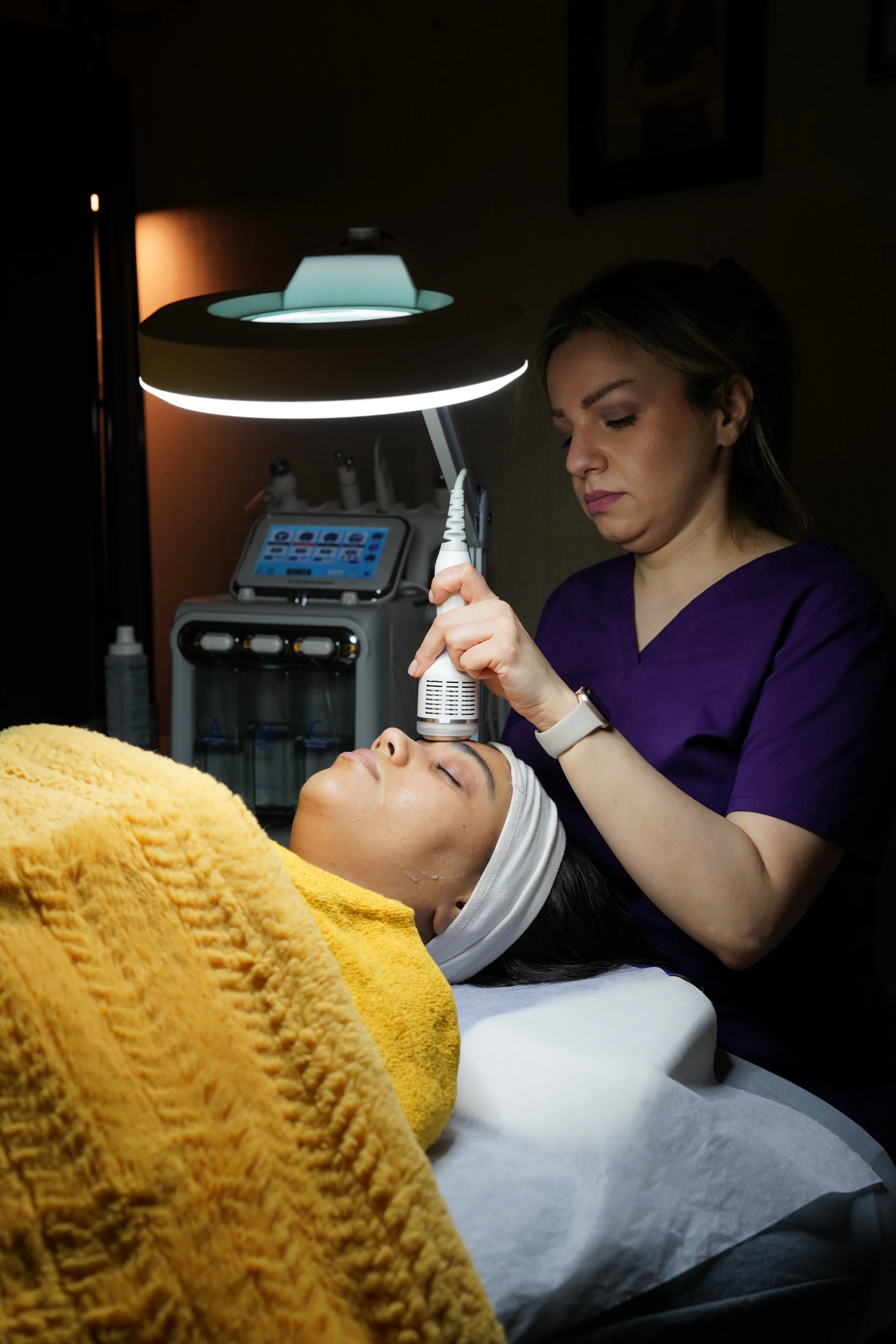 Therapist applying an ultrasound therapy handpiece to the client's forehead
